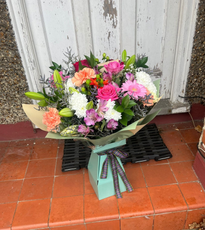 Lavender Garden Hand-Tied - A beautifully arranged hand-tied bouquet bursting with soft pastel charm. This design features an elegant mix of lilac roses, creamy carnations, white chrysanthemums, lilies, and delicate seasonal blooms. Accented with lush greenery and finished in stylish gift wrap with a presentation box and ribbon, this bouquet brings a fresh, romantic feel to any occasion. Perfect for birthdays, thank-yous, anniversaries, or simply brightening someone’s day.