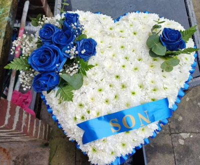 Blue & White Heart Tribute - Various colour options. A beautifully crafted heart-shaped tribute in soft white blooms, accented with striking blue roses and gentle foliage. A meaningful and heartfelt arrangement, designed to honour and remember a loved one with dignity and love.