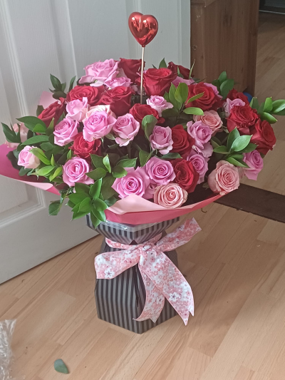 Roses Wow - Stunning hand-tied bouquet of 50 roses in soft pink and vibrant Freedom red, beautifully arranged with mixed foliage for a breath-taking display.